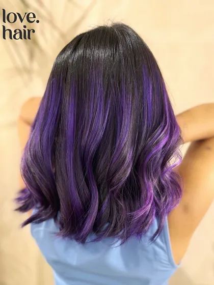 Rang Barse. A Holi-inspired look with vibrant purple highlights woven through dark hair for a festive and fun style.