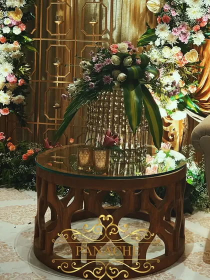 An ornate wooden side table with a mirrored top, reflecting the floral decor and adding another layer of texture to the lounge area.