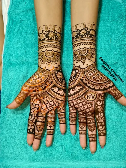 A stunning bridal design featuring a mix of geometric checks, floral bands, and tiny elephant figures. The initials 'N' and 'V' are subtly woven in for a personal touch.