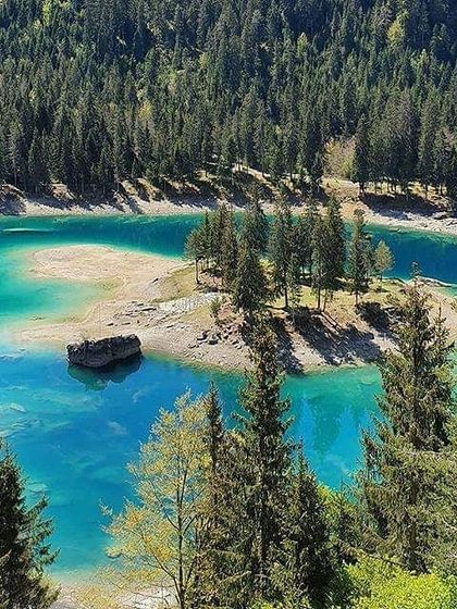 An aerial view of a turquoise lake in Switzerland, its islands like small sanctuaries. The element of water teaches us to be fluid and adaptable, and practicing near it helps us to embody these qualities.