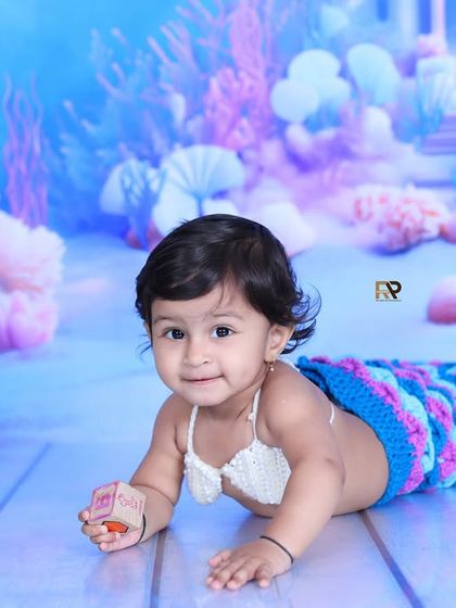 A happy baby mermaid plays with a toy, fully immersed in her magical underwater world. These sessions are designed to be fun and engaging for your little one.