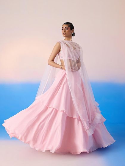 A soft pink tiered lehenga with a sheer cape, a romantic and feminine look for a daytime wedding or reception.