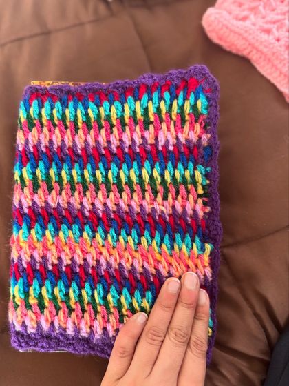 A vibrant, multi-colored book cover in a textured stitch. It's a great way to use up yarn scraps and create something beautiful.