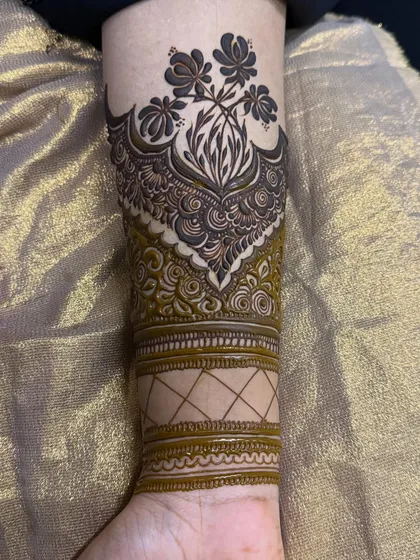 A unique cuff design on the forearm, combining floral elements with traditional band work.