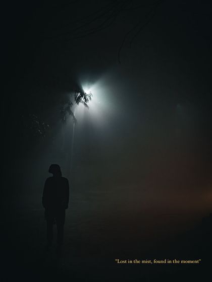 A silhouette of a person stands under a single streetlight on a foggy Delhi morning, a moody photograph about solitude and finding oneself in the mist.
