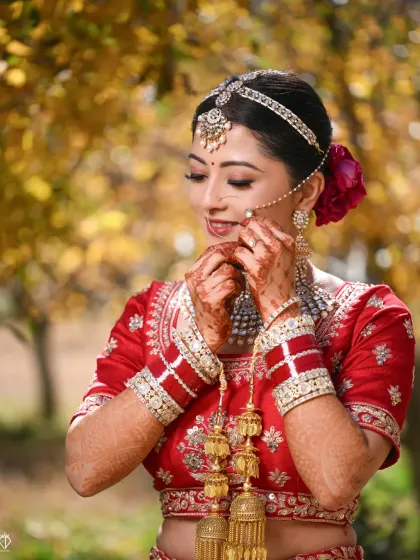 A beautiful candid of the bride adjusting her nath, with the golden autumn leaves creating a warm and picturesque background.