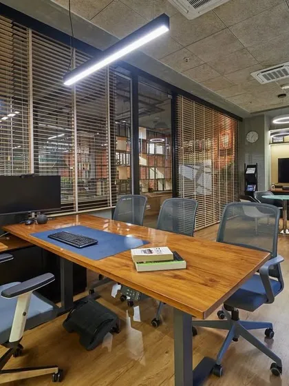 A spacious boss's cabin with a large L-shaped desk and views of the office through glass walls. The design is modern, with clean lines and a focus on functionality.
