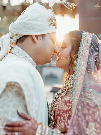 A golden hour kiss, with the setting sun creating a beautiful flare. This romantic portrait captures the warmth and love of the couple on their special day.