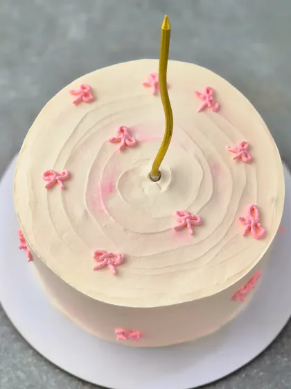 An overhead view of the bow-themed cake, showing the simple design with a single candle.