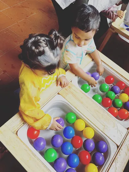 Two children playing side-by-side at the water tables. This shows how our activities encourage parallel play, an important step in developing social skills as they share a space while exploring individually.
