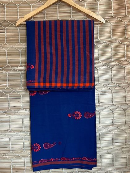 A deep blue handloom saree with contrasting orange and pink embroidery. This piece is a testament to the skill of our artisans, who blend colors and crafts to create something truly special.