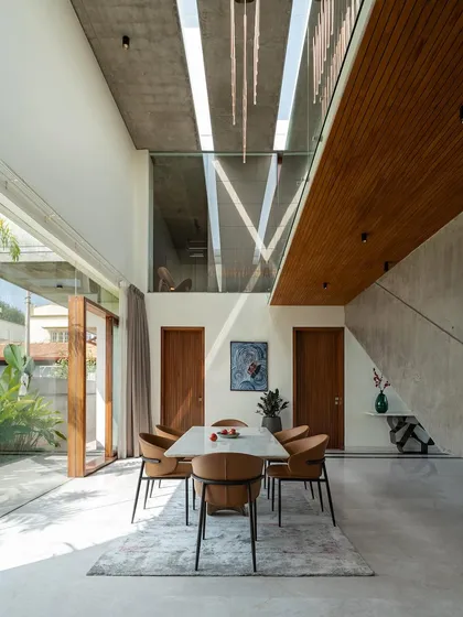The dining area is situated in a double-height space, with skylights and large glass doors creating an airy, sunlit atmosphere. The view looks out onto the garden, making every meal an experience connected to nature.