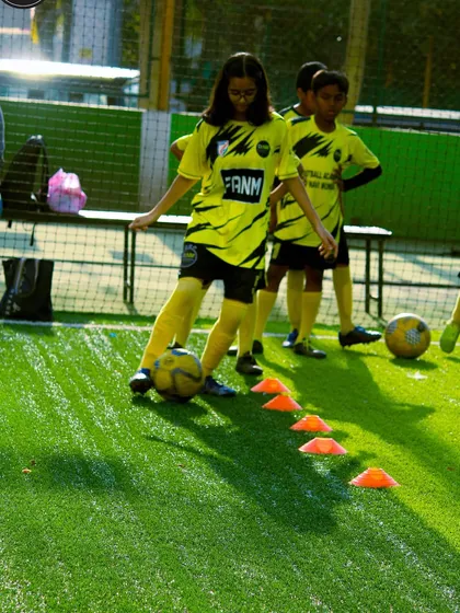 A young girl practices her dribbling through a cone drill, showcasing her focus and developing skill.