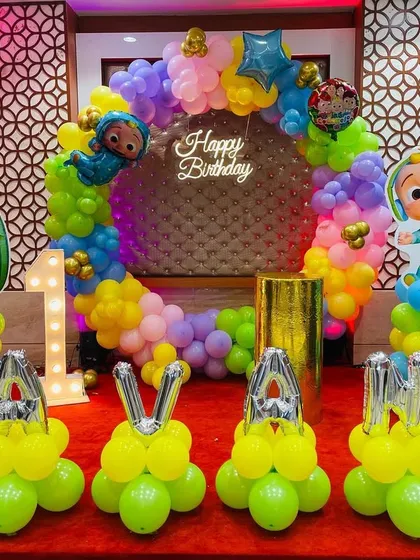 A vibrant Cocomelon party with personalized balloon lettering. I used bright yellow balloons to spell out the birthday girl's name, "PAVANA", in front of a colorful ring backdrop and character cutouts.