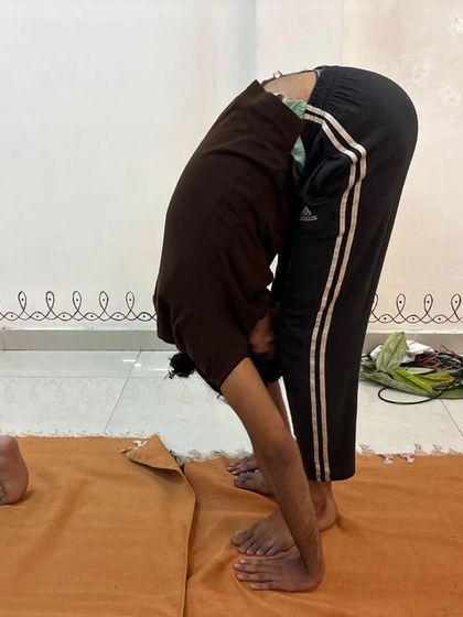 A participant holds Padahastasana during Surya Kriya, a posture that helps to stabilize the mind and energize the system.