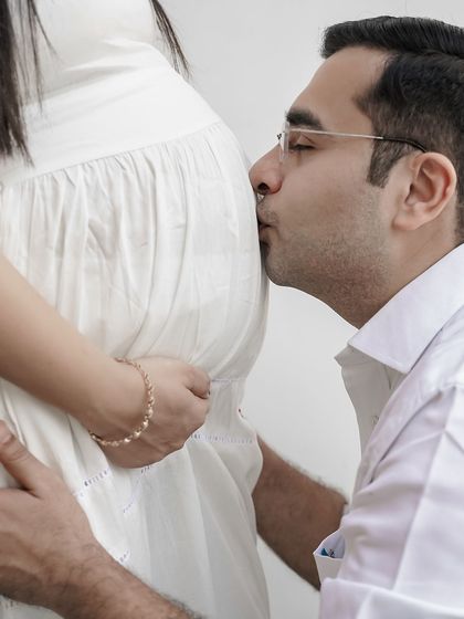 A tender moment captured between expecting parents. The father-to-be gently kisses the baby bump, showing a simple yet powerful expression of love and excitement for their baby.