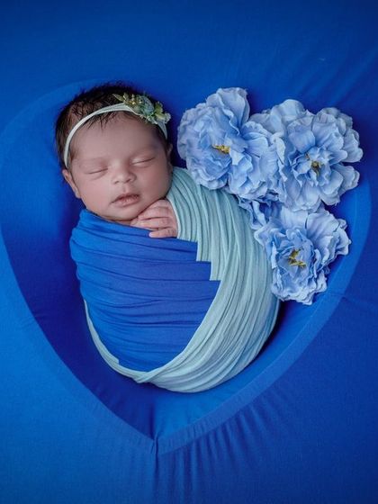 A dream in blue. This photo uses a heart-shaped frame to create a window into the baby's peaceful, floral-adorned sleep.