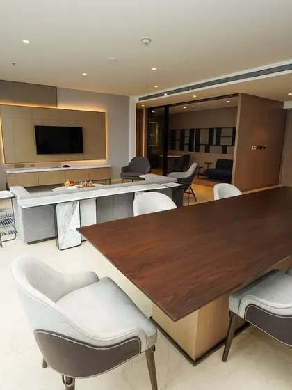 A wide shot capturing the dining area, living room, and a glimpse into the kitchenette, providing a comprehensive view of the suite's open-concept design.