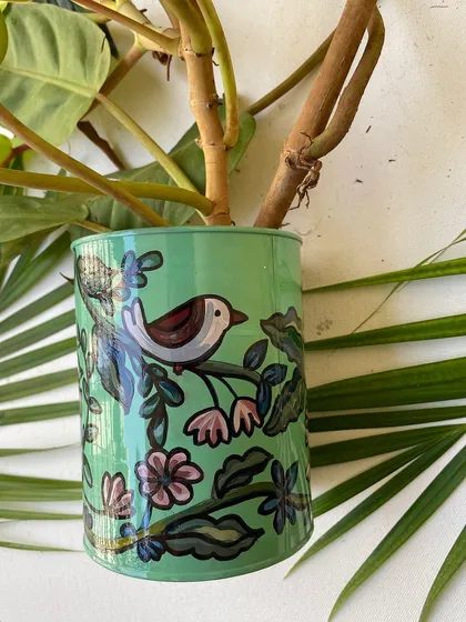 A close-up of a green planter with a simple bird and floral design.