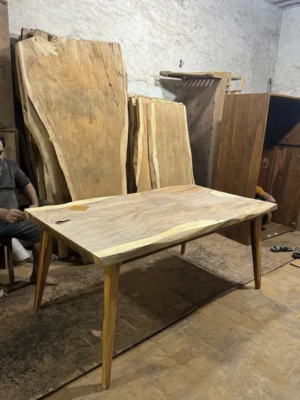 A live-edge table in progress at the workshop. You can see the natural, uncut edge of the wood slab that gives these tables their unique character.