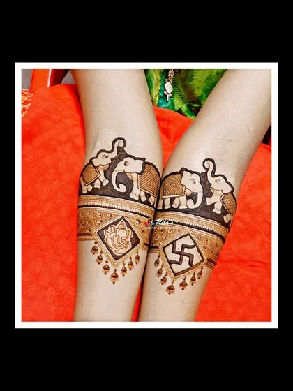 The startup bands on the arms, featuring elephants, Lord Ganesha, and the Swastik symbol. This is a powerful and auspicious start to any bridal design.