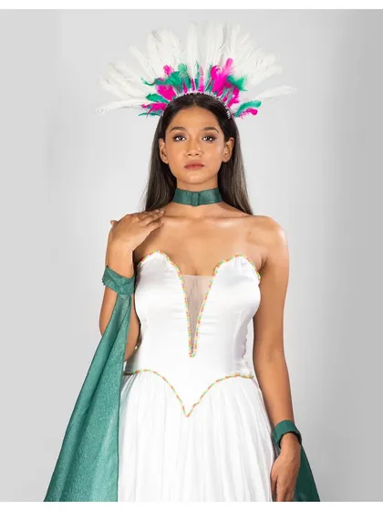 This close-up focuses on the colourful feathered headpiece and the plunging neckline of the gown. The lighting is bright and even, ensuring every detail of the accessories and makeup is sharp and clear.