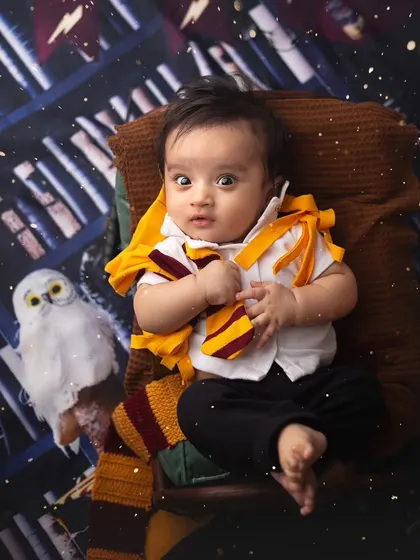 Is that a golden snitch? This little Harry Potter looks so surprised and cute in his wizarding robes, ready for a magical adventure.