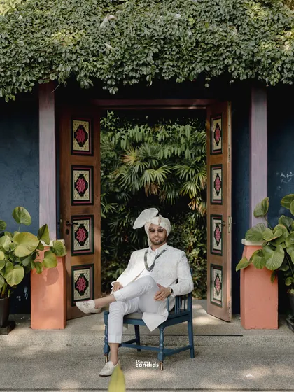 A stylish portrait of the groom seated before a beautifully ornate door, looking cool and confident before his wedding ceremony in Phuket.