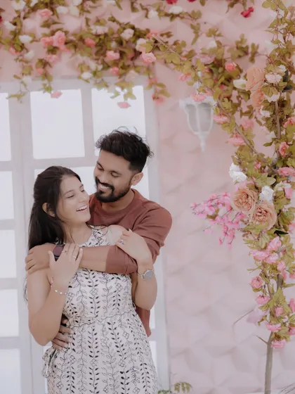 A tender moment against a romantic floral backdrop. The soft pink tones and the couple's gentle embrace create a dreamy and affectionate pre-wedding portrait.