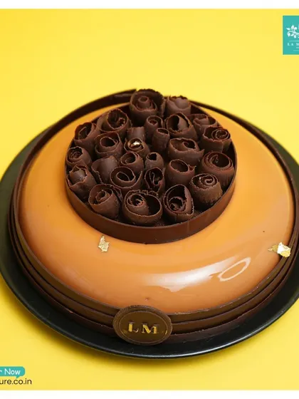 Another view of our Chocolate Orange mirror glaze cake, set against a vibrant yellow background that makes the glossy finish pop.