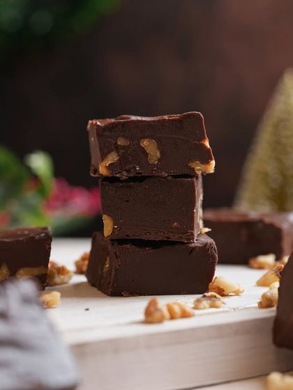 A close-up of stacked chocolate walnut fudge, creating a rich and indulgent feel. Macro shots like this highlight the texture and quality of the dessert.