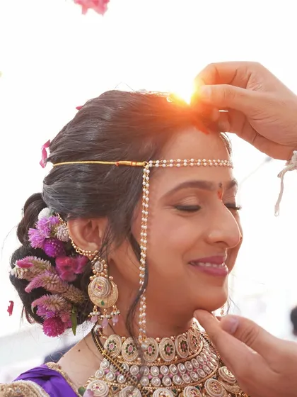 The sacred sindoor ceremony. The makeup remains perfect even in this emotional, close-up moment, with the setting sun adding a magical glow.