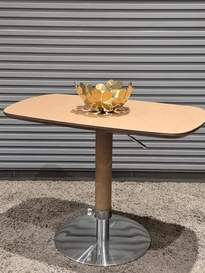 This adjustable-height side table features a polished chrome base and a leatherette-wrapped top, making it versatile for different seating arrangements.