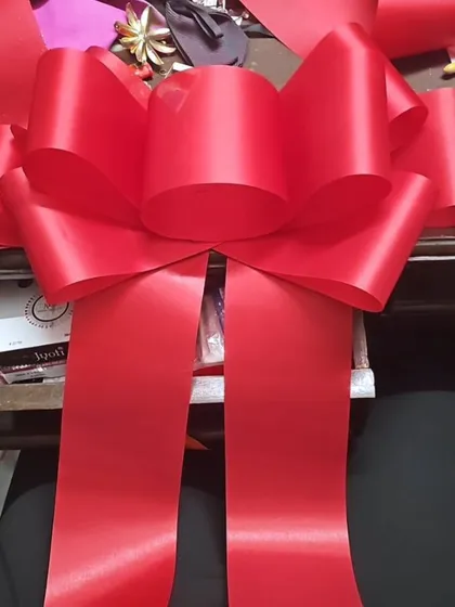 A behind-the-scenes look at the making of a giant celebration bow. Each one is crafted by hand from wide satin ribbon to create that perfect, voluminous shape, ready to adorn a new car, a storefront, or a huge gift.