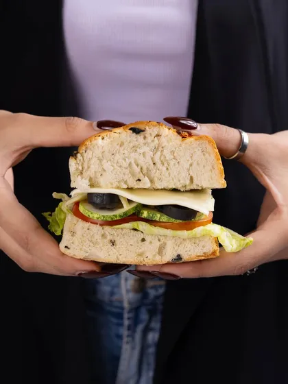 A simple but effective shot of hands holding a freshly made sandwich. This perspective puts the focus entirely on the food and makes it look like a satisfying, hearty meal.