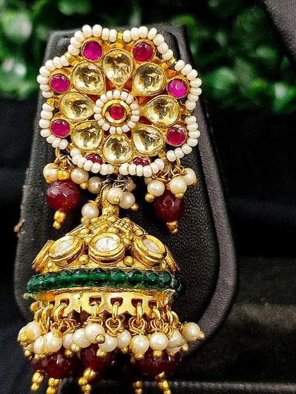 The matching jhumka earring, adorned with red and green stones.