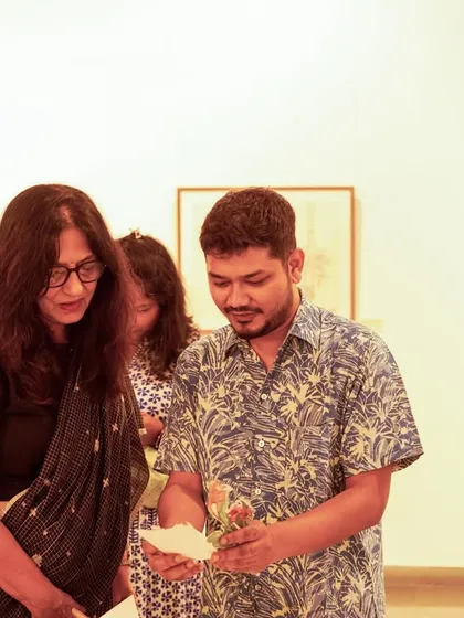 The artist Mohit Mahato showing a small, personal piece to a visitor at his exhibition opening.