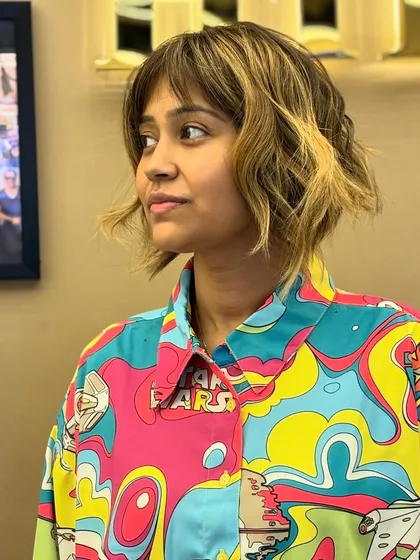 A bold and artistic look, combining a short, choppy bob with blonde highlights and trendy bangs.