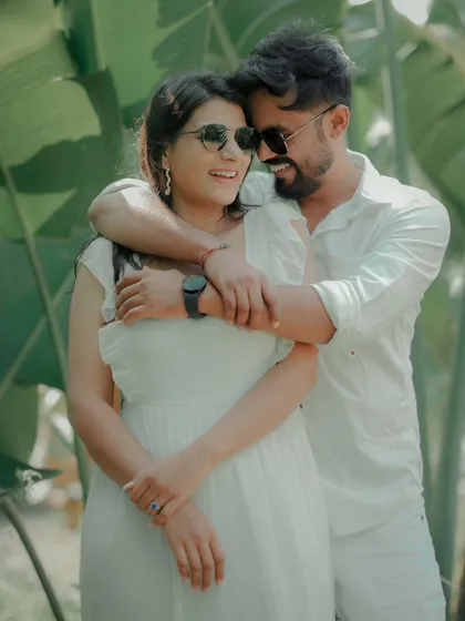 A playful and loving embrace amidst lush greenery. The couple's sunglasses and bright smiles give this candid shot a fun, relaxed vibe, perfect for a sunny day shoot in Pune.