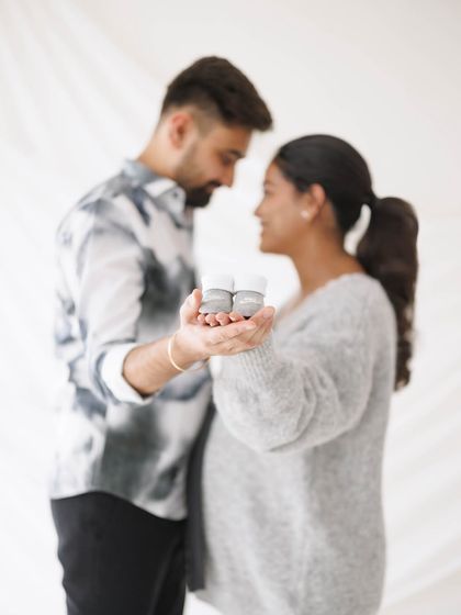 A soft-focus shot that creates a dreamy, intimate feel, with the focus on the tiny baby shoes held between the couple.