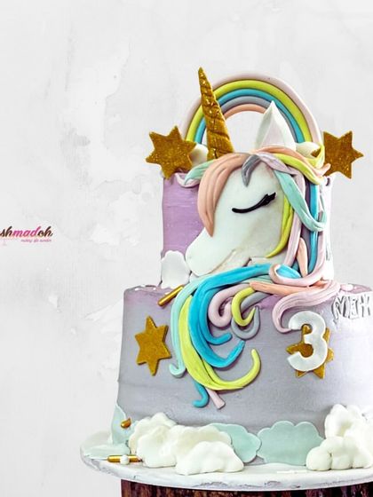A magical two-tiered unicorn cake for a third birthday. The design features a hand-sculpted unicorn, a pastel rainbow, and sparkling edible stars, all made with love.