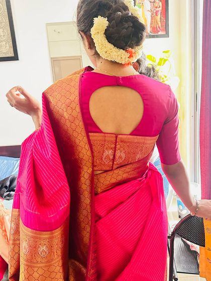 A back view of a client's blouse, featuring a simple circular cut-out design that adds a modern touch to her pink Kanchivaram saree.