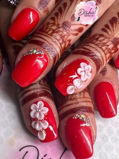 A perfect bridal look. This set features a classic red polish with intricate 3D flowers and rhinestone details, beautifully complementing the traditional henna.
