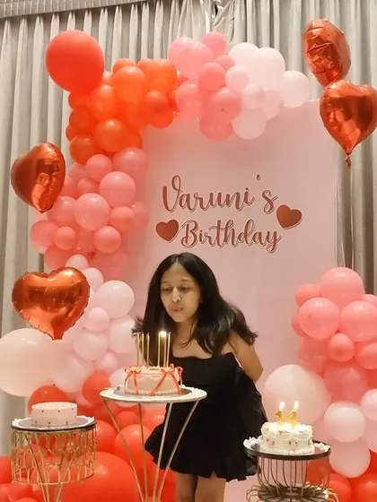 The birthday girl making a wish at her lovely heart-themed celebration.