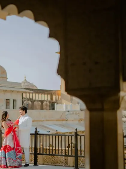 Using the palace archways to frame the couple, this shot creates a sense of depth and intimacy. The fort in the background firmly roots this romantic moment in the royal landscape of Jaipur.