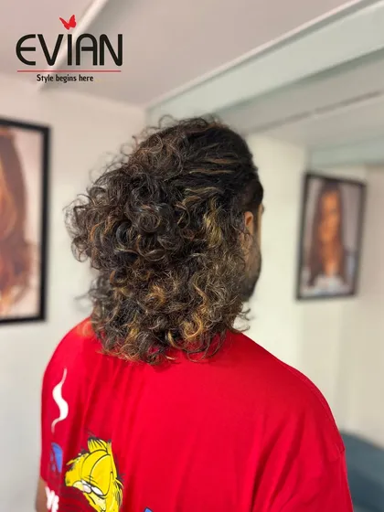 The final result of the highlights on long, curly hair. The lighter pieces add dimension and a sun-kissed effect, making his curls pop.