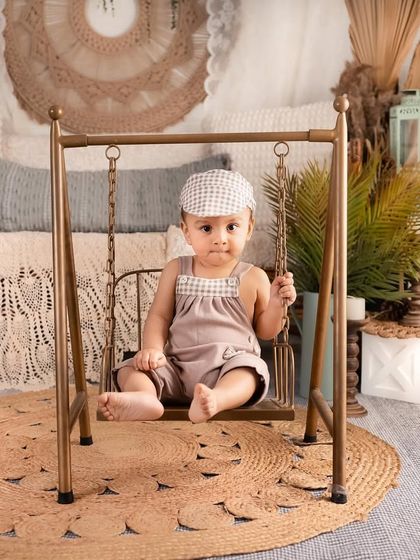 This little boy is having fun on a mini swing in our studio. The bohemian decor in the background adds a layer of texture and warmth to this playful portrait.