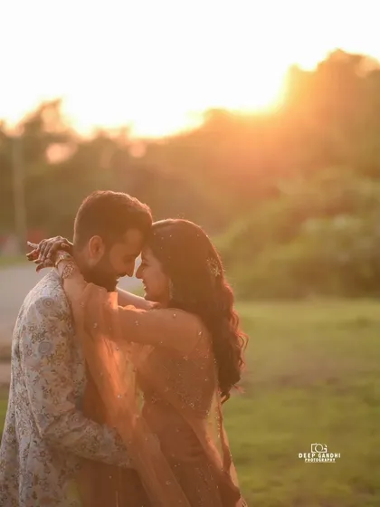A classic romantic portrait of a couple embracing in a field during the golden hour, with the warm sunset creating a soft, dreamy haze that perfectly frames their connection.