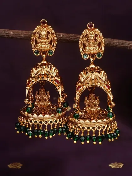 For a classic look, I offer these matte gold finish temple jhumkis with emerald green bead drops. The Goddess Lakshmi motif adds a divine touch.