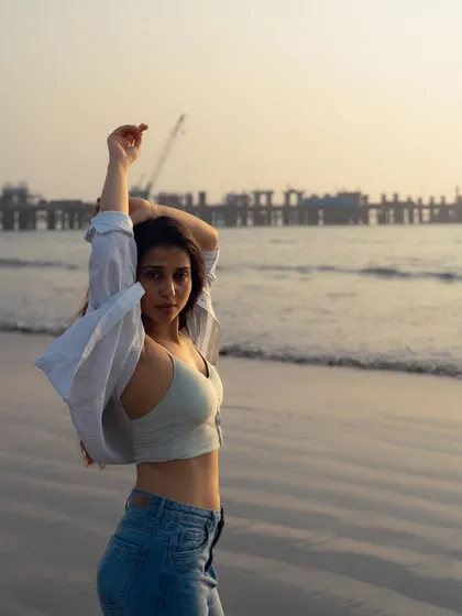 A graceful, reaching pose against the evening sky. This shot has a sense of hope and openness, enhanced by the wide expanse of the beach.